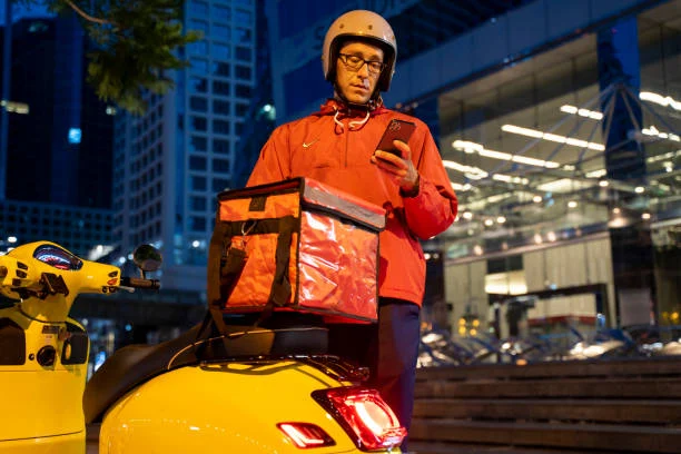 Delivery man driving a scooter through the city at night Delivery man driving a scooter through the city at night